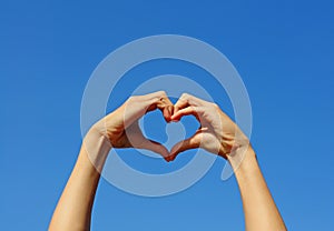 Hand making the sign of Love with the blue sky background