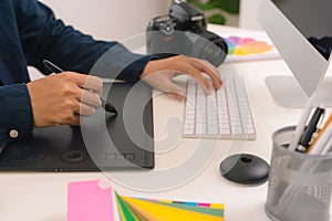 Hand of male designer working at his desk using stylus and digital graphics tablet