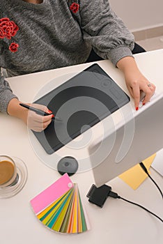 Hand of male designer working at his desk using stylus and digital graphics tablet