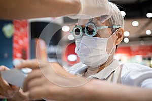 Hand of a male doctor changing lenses in eye testing glasses or trial frame to diagnose senior woman vision,old people eyesight is