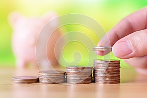 Hand of male or female putting coins money stack step growing growth saving money with piggy bank. Concept finance business