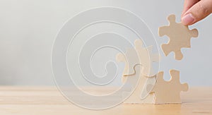 Hand of male or female putting jigsaw puzzle connecting on wooden desk and wall background, Strategic management and business sol