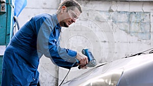 Hand male mechanic wearing suit for working in garage for safety in risky work, wear dustproof goggles, mechanic standing