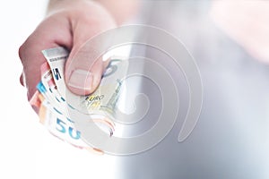 Hand of male person handing over different euro bills