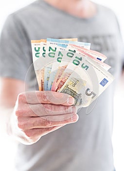 Hand of male person handing over different euro bills