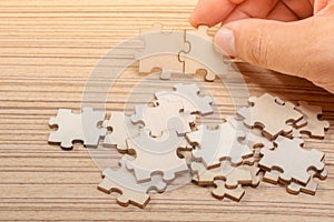 Hand of male trying to connect pieces of jigsaw puzzle