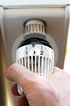 Hand of man adjusting radiator thermostat valve to moon night icon, symbol for saving money at heating costs or low temperature