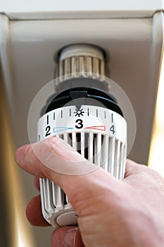Hand of man adjusting radiator thermostat valve to number 3 icon, symbol for saving money at heating costs or medium temperature