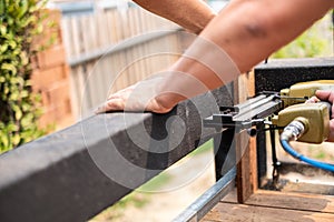 Hand man carpenter using air nail gun to complete wood table in garden