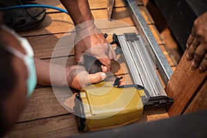 Hand man carpenter using air nail gun to complete wood table in garden