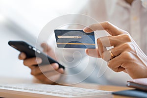 Hand of man in casual shirt paying with credit card and using smart phone for online shopping making orders via the Internet using