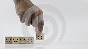 Hand of man choose a happy face on wood block cube on white background.
