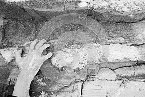 The hand of a man clings to a ledge on a stone. Rock covered with snow