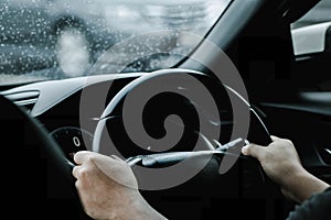 The hand of a man driving on the road on a rainy day. hands of a man with car steering wheel is ready on the move in the modern