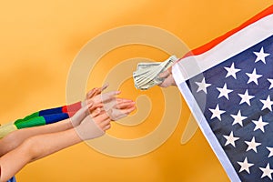 The hand of a man flying the American flag hands money to childrenï¿½s hands, the concept of dependence on the USA