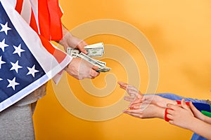 The hand of a man flying the American flag hands money to childrenï¿½s hands, the concept of dependence on the USA