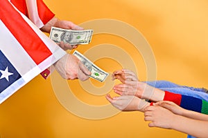 The hand of a man flying the American flag hands money to childrenï¿½s hands, the concept of dependence on the USA