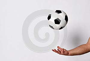 Hand of a man with golden wedding ring on his finger is throwing up a soccer ball, isolated on white studio background. Close up