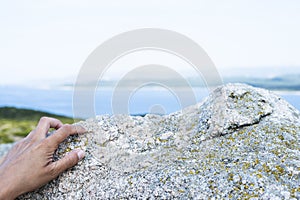 The hand of a man gripping a rock outdoors