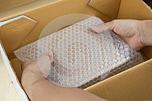 Hand of man hold Bubbles covering the box by bubble wrap for protection product