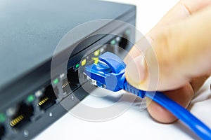 Hand of man holding The blue network cables connect port switch on white table