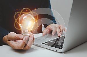 Hand man holding bulb light idea creativity inspiration and using computer laptop on desk
