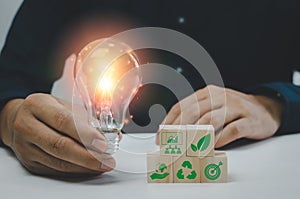 Hand man holding bulb light and wood cube green eco environmental and net zero concept