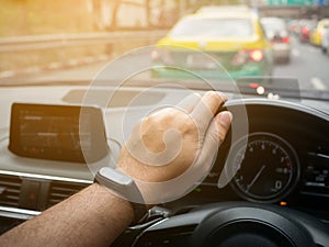 hand of man holding and controls steering wheel of his car, traveling in the city on the traffic jam road