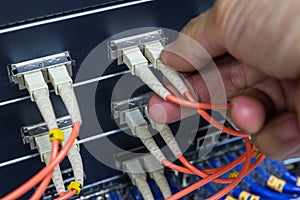Hand of man holding The Fiber Optic Cable to connect SFP module port