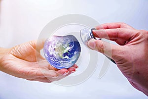 Hand man holding heart earth and  listening to heart earth with a stethoscope on blue background.