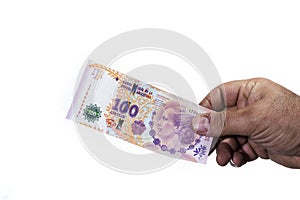Hand of man holding a hundred Argentinean peso bill in which the photo