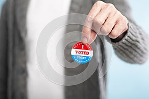 Hand of man holding an I voted today sticker with American Flag