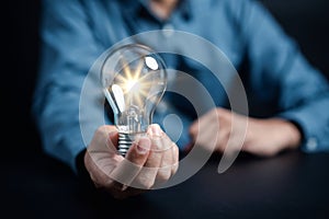 Hand man holding illuminated lightbulb, idea, innovation and inspiration with glowing virtual brain, smart intelligent creativity