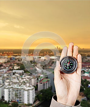 The hand of a man holding a magnetic compass over a city buildings