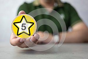 Hand of a man holding a smile face on wood block circle. Customer service experience and satisfaction survey