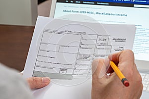 The hand of the man holding the Tax Form 1099-misc