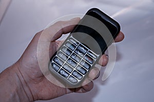 The hand of a man holds an old push-button telephone.