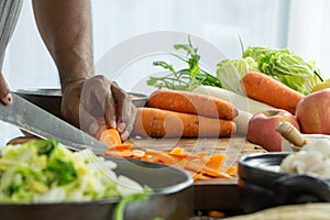 hand of man with a knife cut a fresh carrot with vegatable for cooking copy space