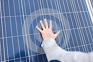 The hand of man lies on the panel of a solar battery.