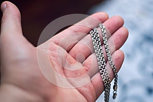 On the hand of a man lies a silver chain, close-up