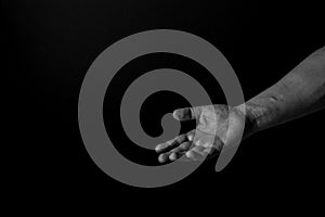 Hand of a man palm up reaching, on black background, giving a helping hand. Give me your hand concept. photo
