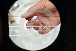 Hand Of Man Playing Acoustic Guitar Viewed From Inside Hole