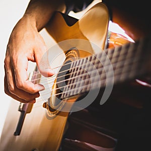 Hand of a man playing an wooden acoustic guitar on a white background