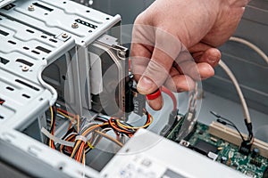 Hand of man plugging SATA Serial AT Attachment, Serial ATA data cable in hard drive device. Computer bus interface to connect ma