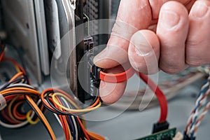 Hand of man plugging SATA Serial AT Attachment, Serial ATA data cable in hard drive device. Computer bus interface to connect ma