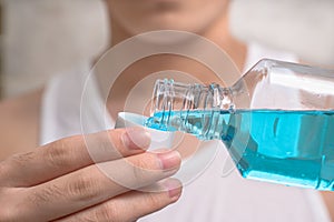 Hand of man Pouring Bottle Of Mouthwash Into Cap