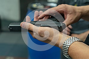 A hand of man practicing firing using a Glock gun model at the shooting range. Fire glock hand gun. man`s hands loading a pistol
