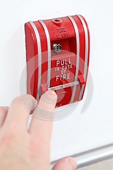 The hand of man is pulling fire alarm