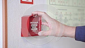 The hand of man is pushing fire alarm on the wall. Clip. Hand of man pushing fire alarm switch on the white wall as