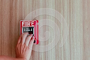 The hand of man is pushing fire alarm on the wall. Hand of man pushing fire alarm switch on the white wall as background for emerg